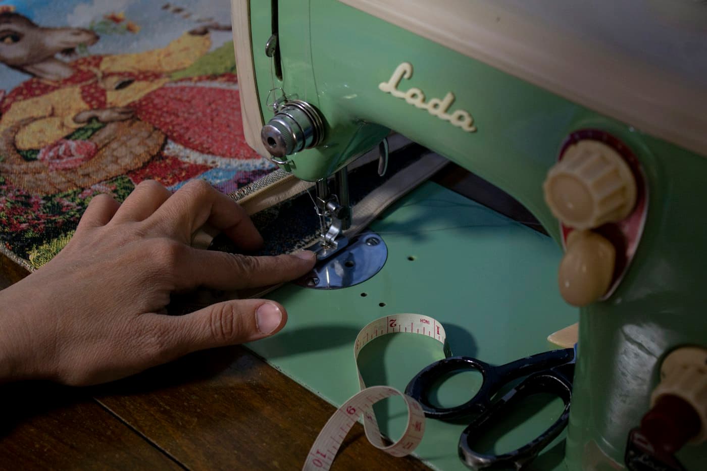 Hands guiding fabric through a vintage sewing machine